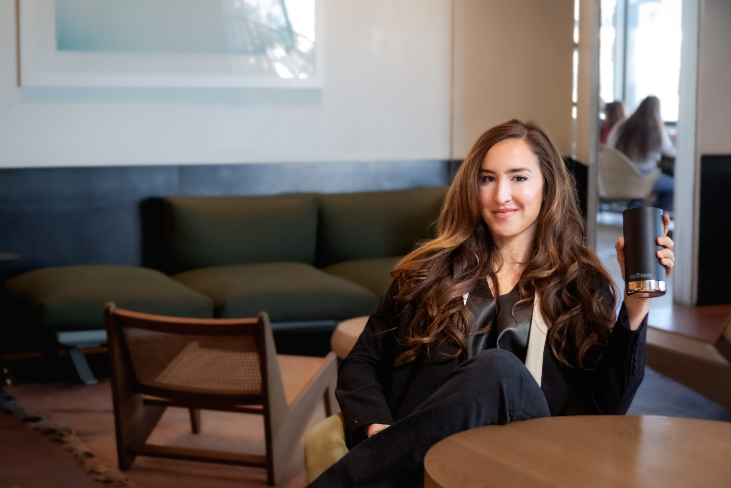 Codie Sanchez sits in an office lounge with a tumbler of coffee.